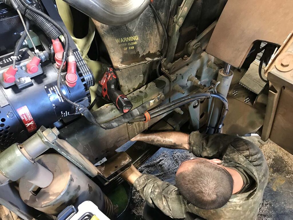 A wheeled vehicle mechanic assigned to the 25th Composite Truck Company, 25th Sustainment Brigade, addresses a radiator hose leak on an FMTV series vehicle, at Schofield Barracks, Hawaii, on 30 May 2018. [US Army]
