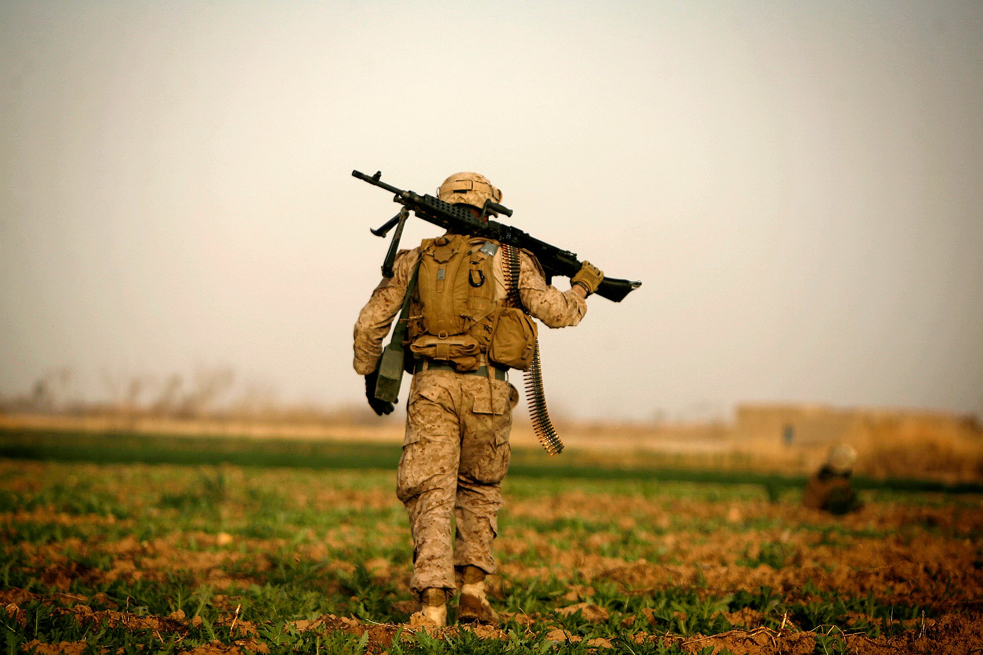 A US Marine with 1/3 Marines Weapons company carries an M240 machine gun over his shoulder during a patrol over farmland in the northeast of Marjah on February 14, 2010. Some 15,000 soldiers, including 4,400 Afghans, are taking part in Operation Moshtarak, which aims to clear militants from the Marjah and Nad Ali districts of the poppy-growing central Helmand River valley. AFP PHOTO/PATRICK BAZ (Photo credit should read PATRICK BAZ/AFP via Getty Images)