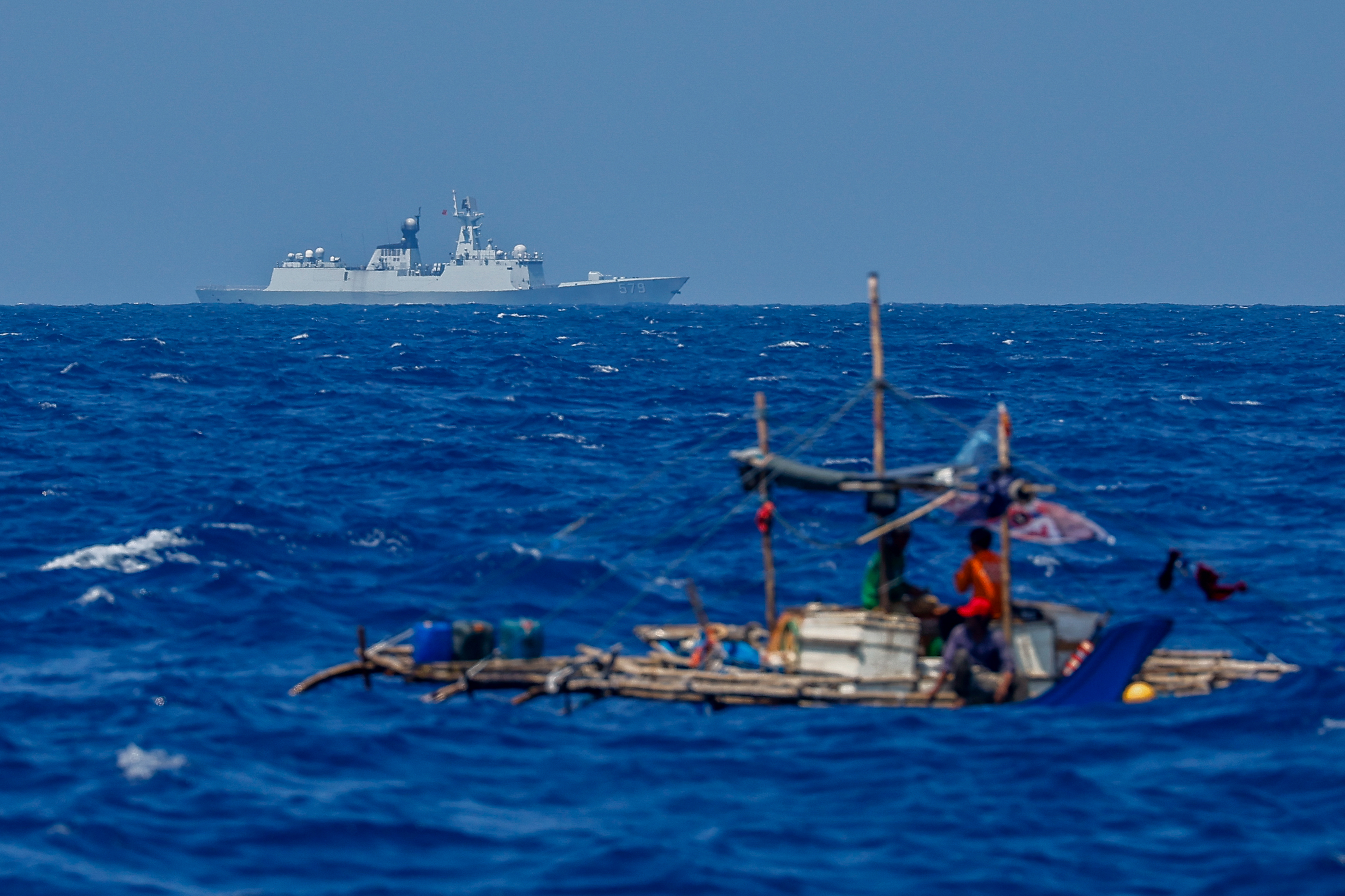 A Filipino fishing boat is seen as a Chinese Jiangkai 579 warship sails near a fleet of U.S. and Philippines naval vessels in the West Philippine Sea, April 26, 2025. (Daniel Ceng/Anadolu via Getty Images)