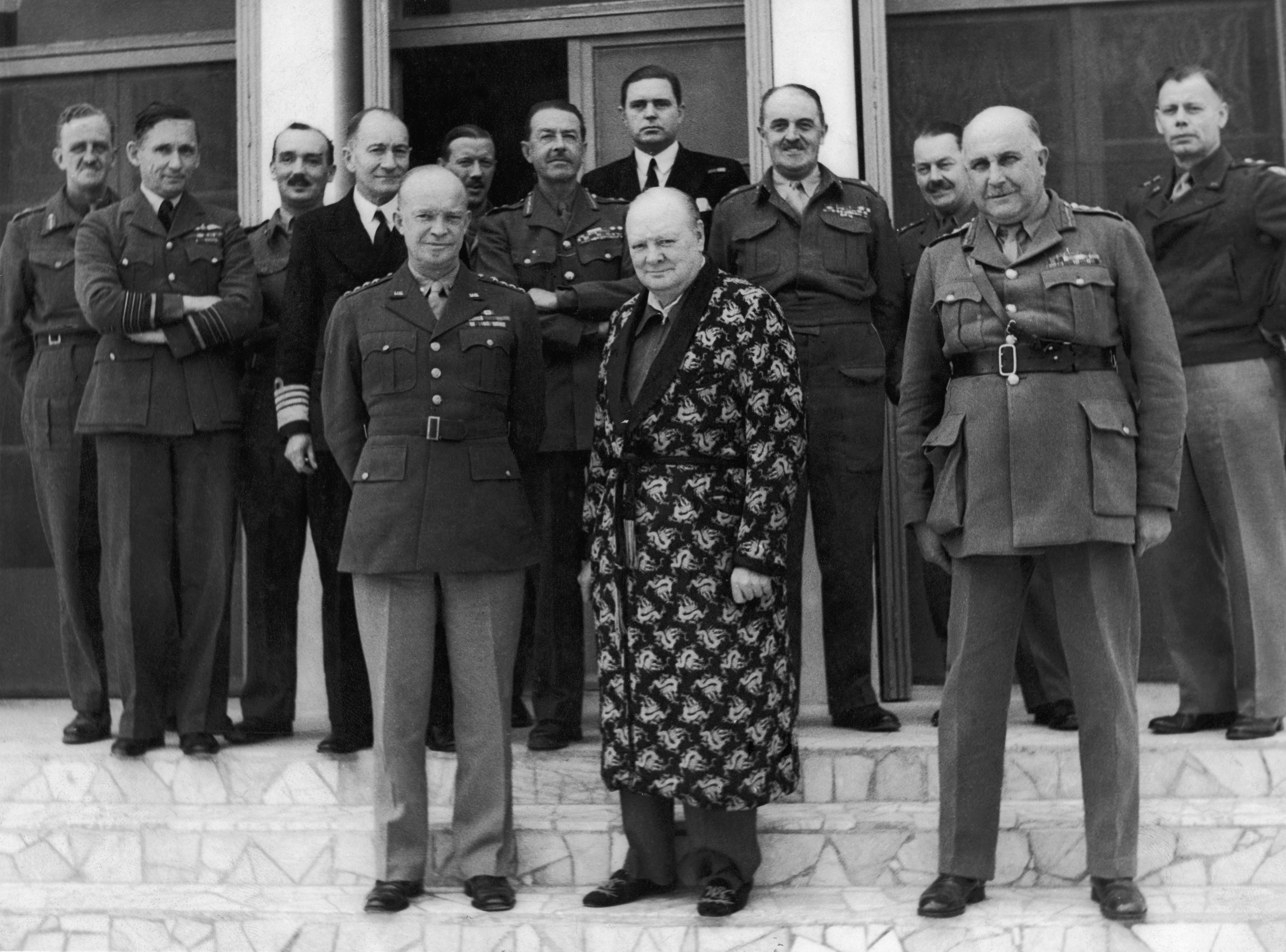 Winston Churchill, dressed in his siren suit and gown, pictured with senior officials, including Gen. Dwight Eisenhower (front left). (Daily Mirror/Mirrorpix via Getty Images)