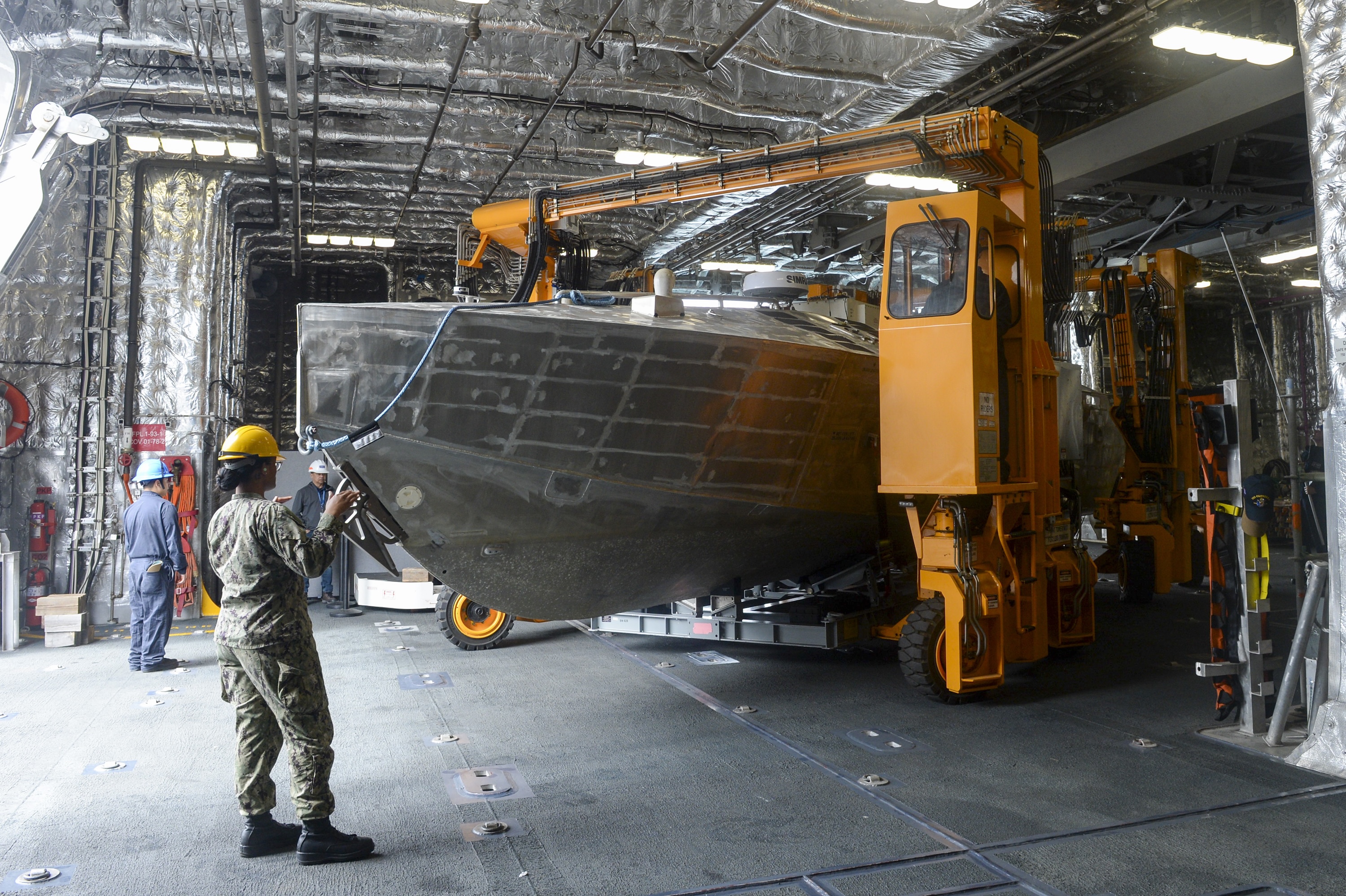 Sailors aboard the USS Canberra transport an unmanned surface vehicle in the ship’s mission bay, as part of the first embarkation of the MCM mission package, April 23, 2024. (MC1 Vance Hand/U.S. Navy)