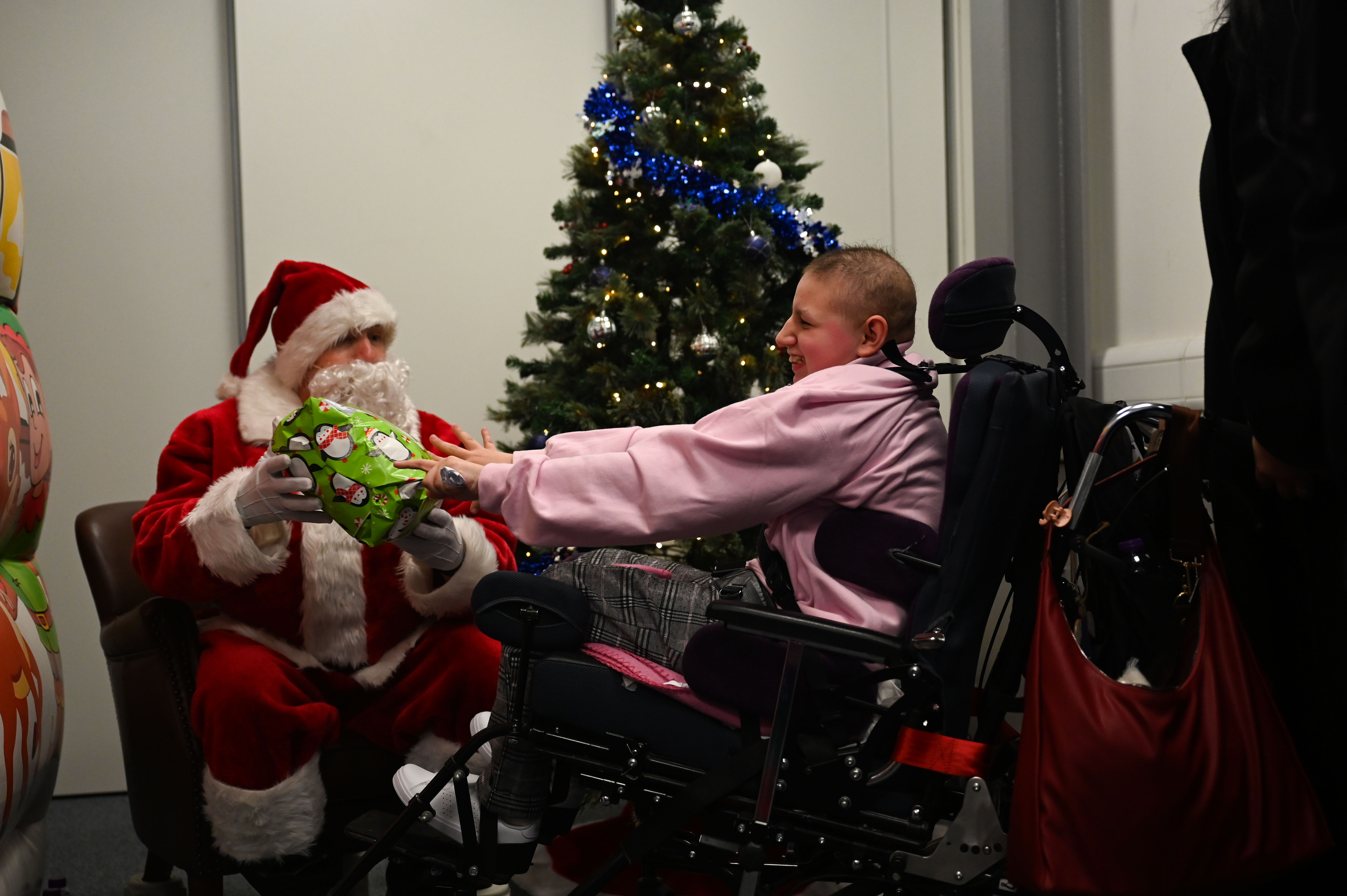 U.S. Air Force Lt. Col. David Bervig, 492nd Fighter Squadron commander, gives a gift to a child from the East Anglia Children’s Hospices at the Imperial War Museum Duxford, Cambridge, England, Dec. 6, 2025. The squadron hosted its annual Christmas party in order to give back to the local community. (U.S. Air Force photo by Staff Sgt. Elizabeth Davis)