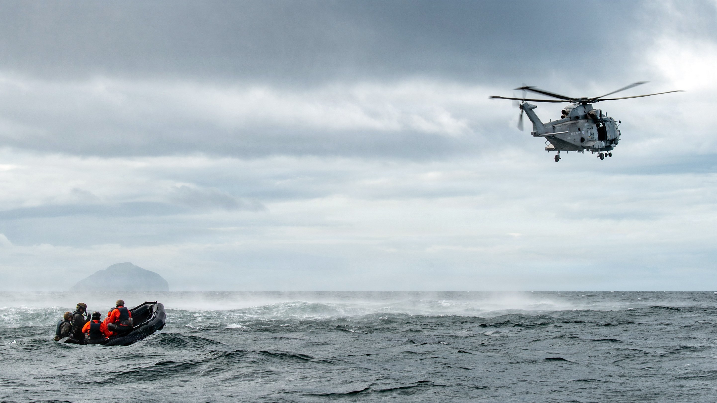 U.S. Airmen from the Kentucky Air National Guard’s 123rd Special Tactics Squadron prepare to hoist a simulated patient into a Merlin Mk2 helicopter off the coast of Scotland on Aug. 18, 2026, as part of a search-and-rescue training scenario. The helicopter is assigned to the British Royal Navy’s 814 Naval Air Squadron. (U.S. Air National Guard photo by Phil Speck)
