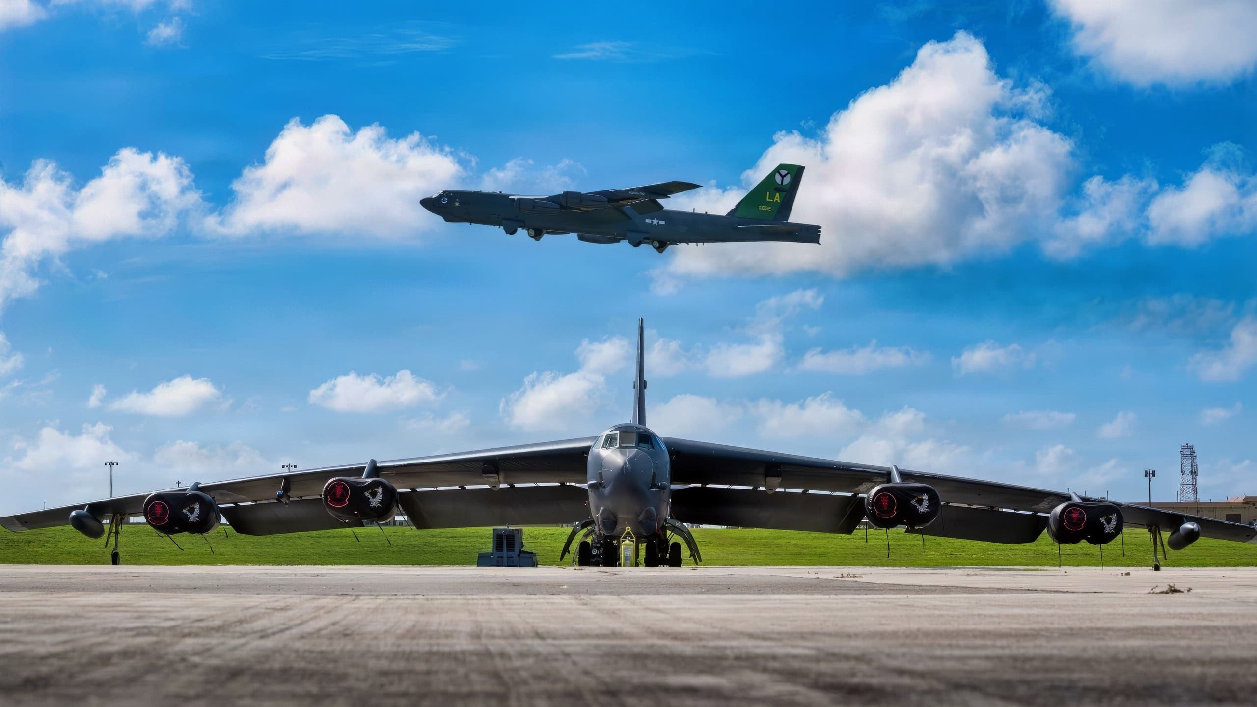 The 2nd Bomb Wing flagship B-52H Stratofortress flies over another B-52H parked on the flightline at Andersen Air Force Base, Guam, Feb. 10, 2026.Andersen Air Force Base, Guam, Feb. 10, 2026. The B-52 is a long-range, strategic bomber, and its presence demonstrates the United States’ ability to project power and respond to crises anywhere in the world. (U.S. Air Force photo by Airman 1st Class Devyn Taylor)