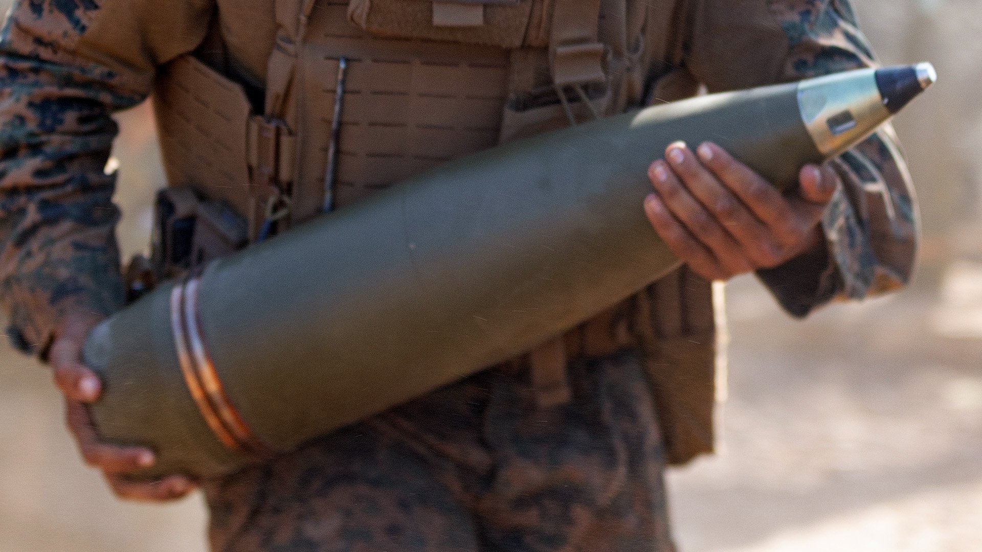 Soldier holding 155mm artillery shell for Ukraine ammunition supply