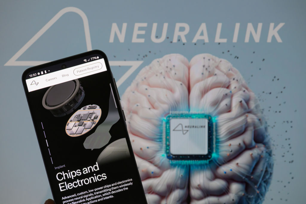 The Neuralink website is displayed on a mobile phone with Neuralink visible in the background. (Jonathan Raa/NurPhoto via Getty Images)