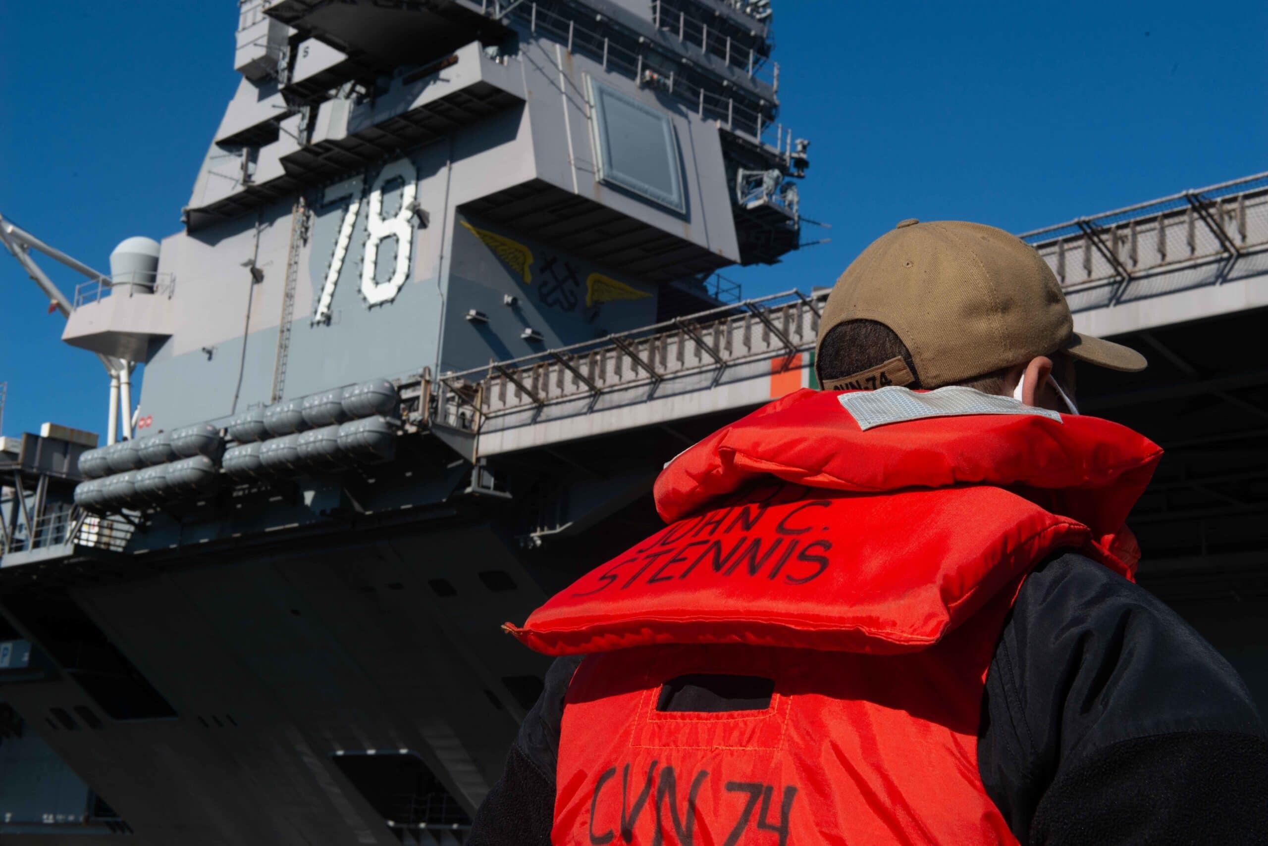 A U.S. Navy Sailor assigned to the aircraft carrier USS John C. Stennis (CVN 74), stands at parade rest as the aircraft carrier USS Gerald R. Ford (CVN 78) pulls into port in Norfolk, Va., Nov. 20, 2020. The John C. Stennis is partnering with Newport News Shipbuilding to complete Refueling Complex Overhaul on schedule with a trained, resilient and cohesive crew. (U.S. Navy photo by Mass Communication Specialist Seaman Apprentice Curtis Burdick)