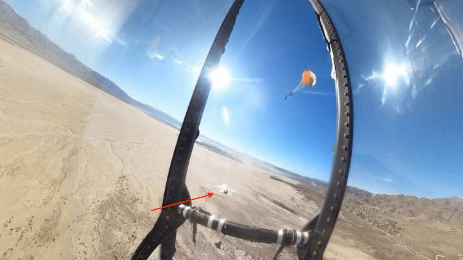 An image caputured by an in-cockpit camera of a Thunderbird pilot under a parachute after ejecting on Dec. 5, 2025. The F-16 can be seen continuing to fly beneath the pilot.