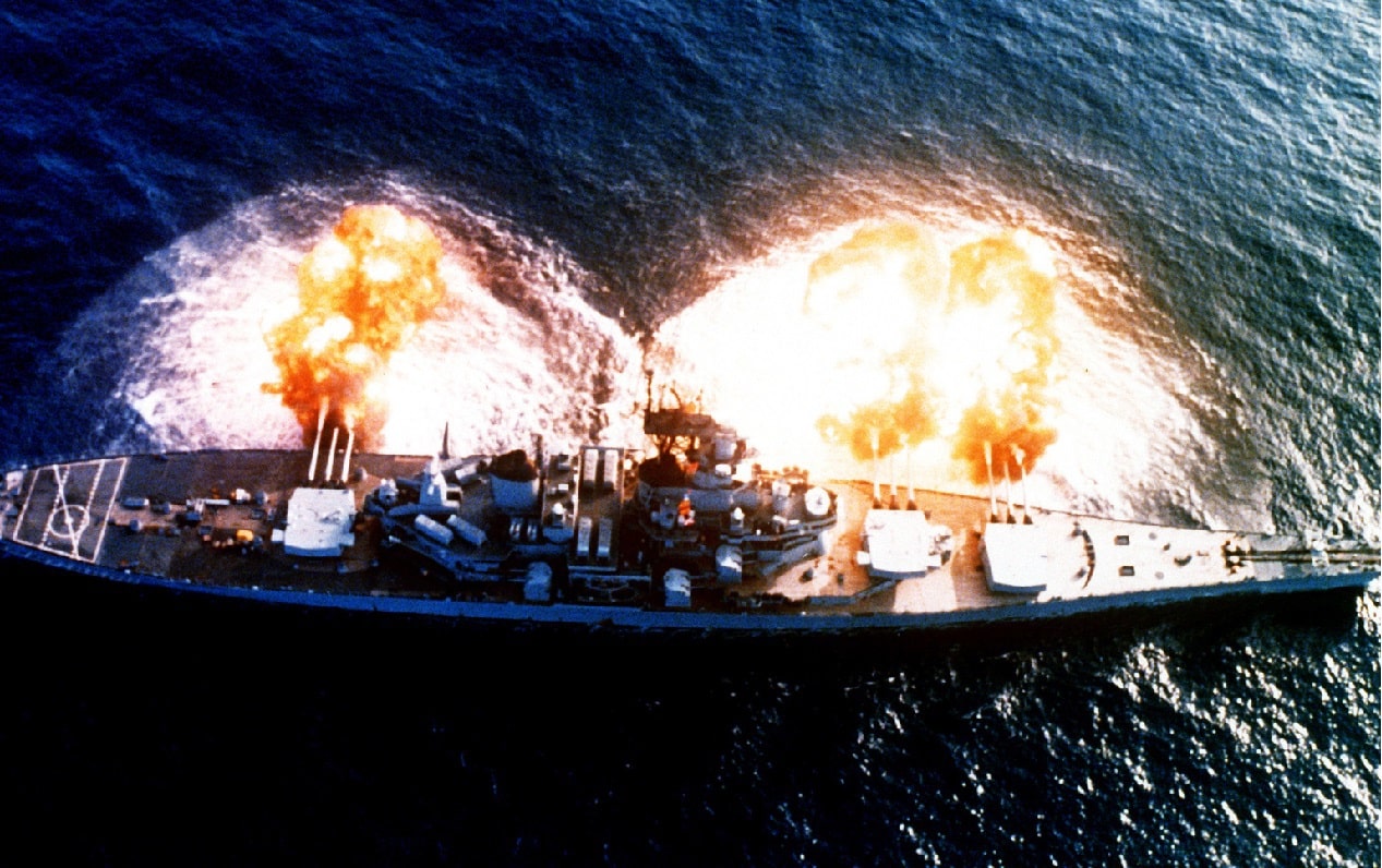 An overhead view of the battleship USS NEW JERSEY (BB-62) firing a full broadside to starboard during a main battery firing exercise. Image Credit: Creative Commons.