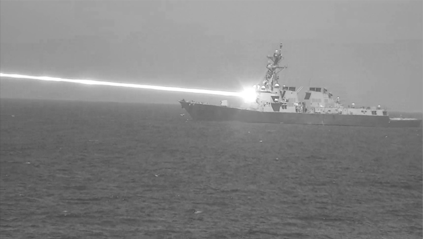 The USS Preble uses the High-Energy Laser with Integrated Optical Dazzler and Surveilleance (HELIOS) system to beam a laser at an unmanned aerial vehicle target during weapons testing.