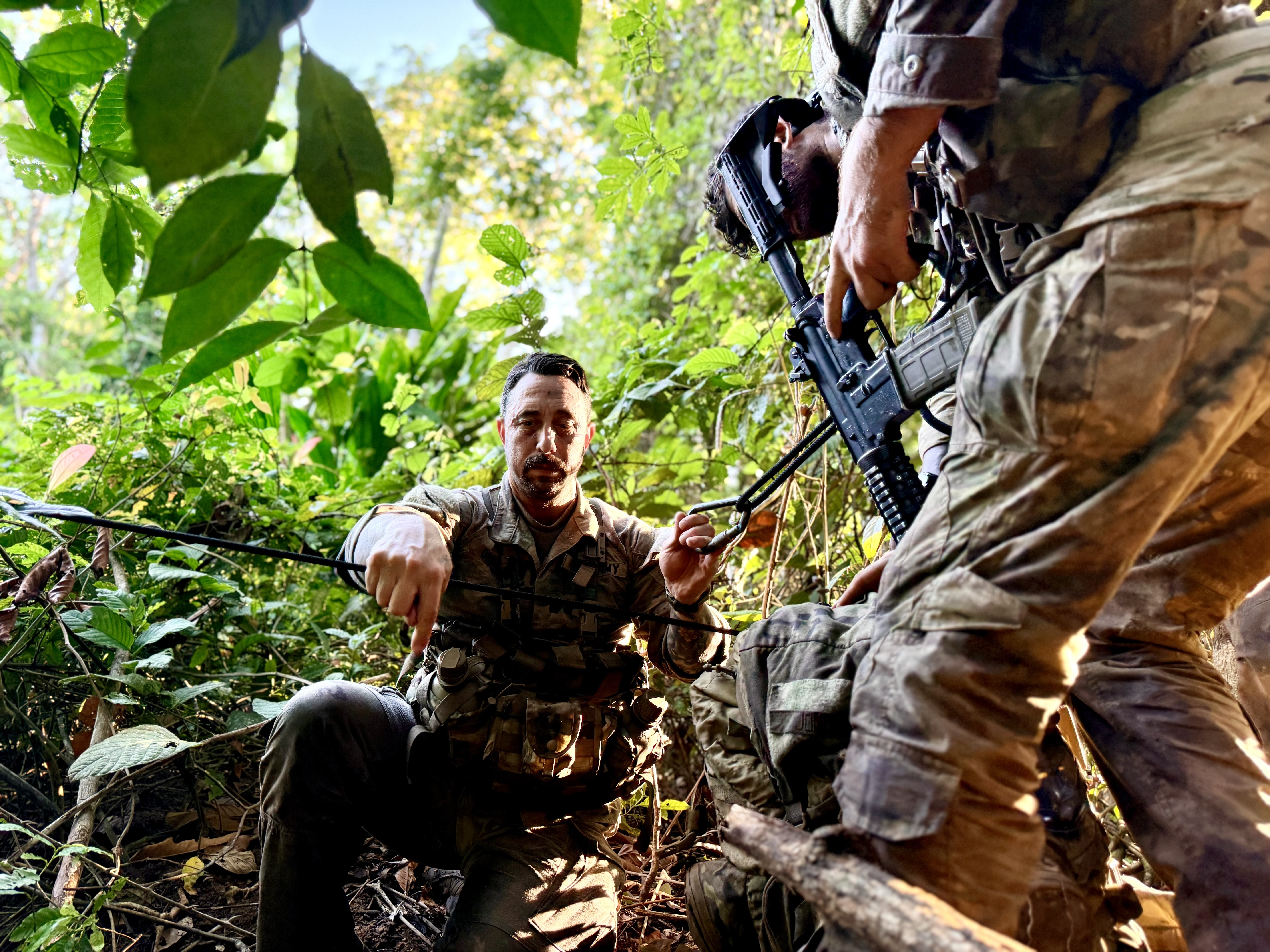 A service member attending the U.S. Army's Jungle School in Panama assists with a one-rope bridge across a waterway in September 2026. (Eve Sampson/staff)