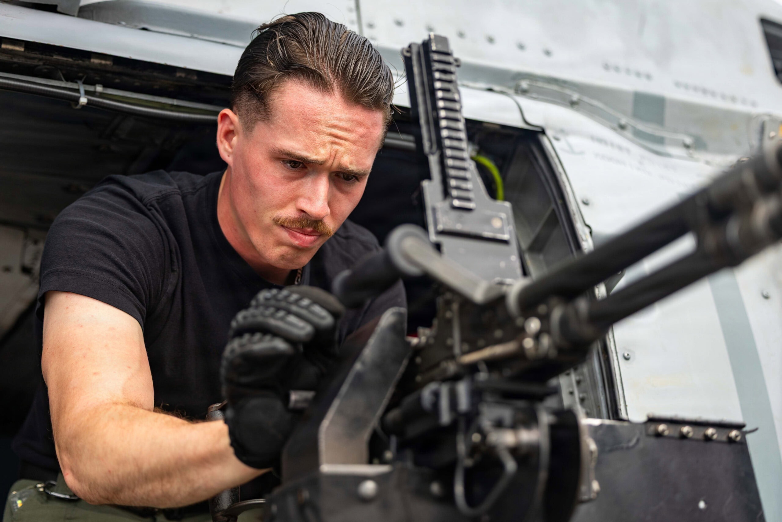 U.S. Navy Naval Air Crewman (Helicopter) 2nd Class Justin Baker, from Illinois, assigned to Helicopter Maritime Strike Squadron (HSM) 51, executes a safety and function check on an M240D machine gun on an MH-60R Sea Hawk helicopter on the flight deck of Arleigh Burke-class guided-missile destroyer USS Rafael Peralta (DDG 115) in the South China Sea, March 25, 2026. Rafael Peralta is forward-deployed and assigned to Destroyer Squadron (DESRON) 15, the Navy's largest DESRON and the U.S. 7th Fleet's principal surface force. (U.S. Navy photo by Mass Communication Specialist 1st Class Ryre Arciaga)