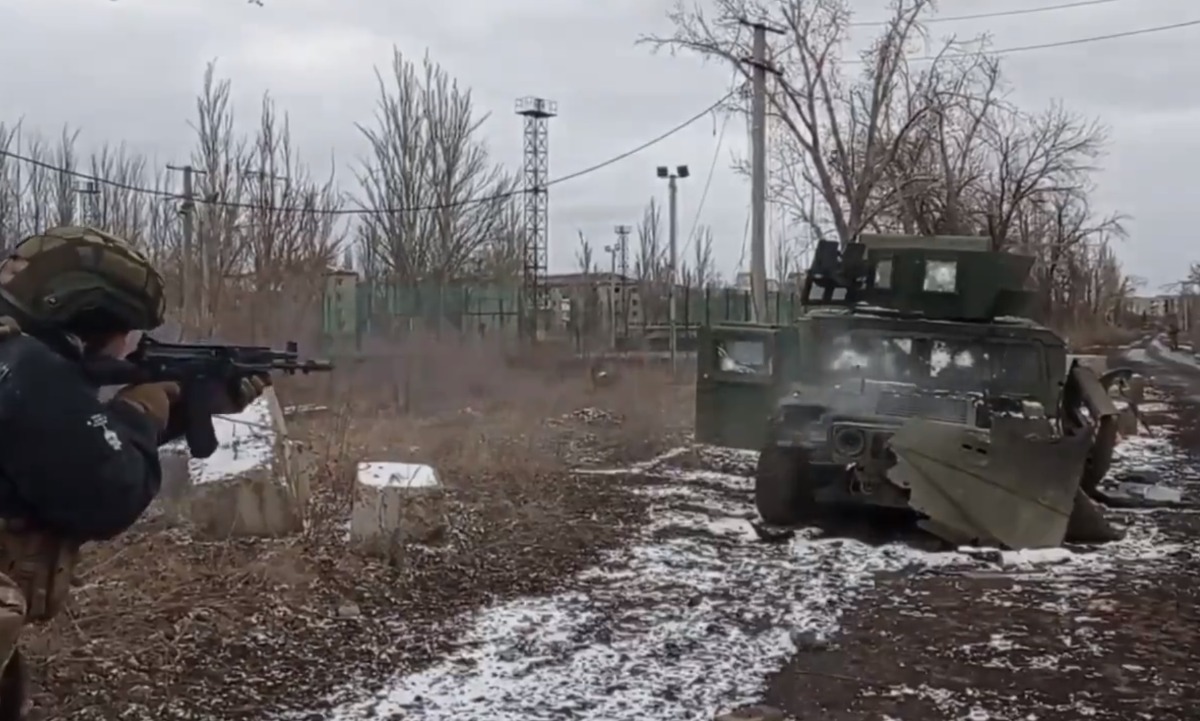 A Russian soldier fires an assault rifle at point-blank range at a captured Ukrainian Humvee during an informal armor test.