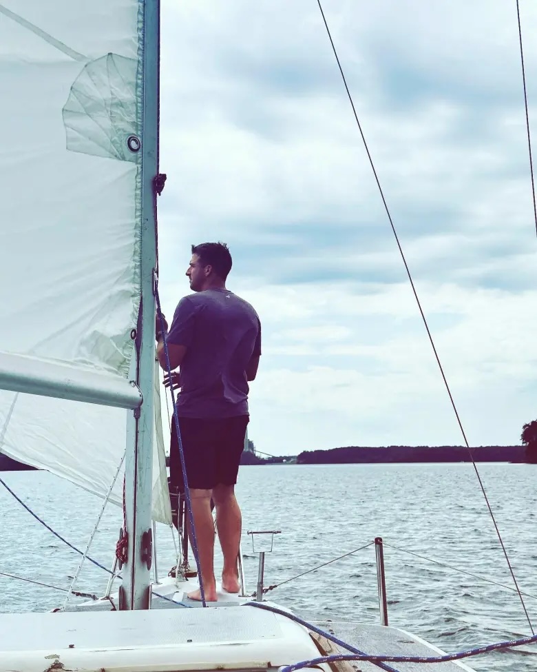 Evan Slusser just after raising the sail on a fixer-upper boat he had bought and repaired. (Photo courtesy of the author)