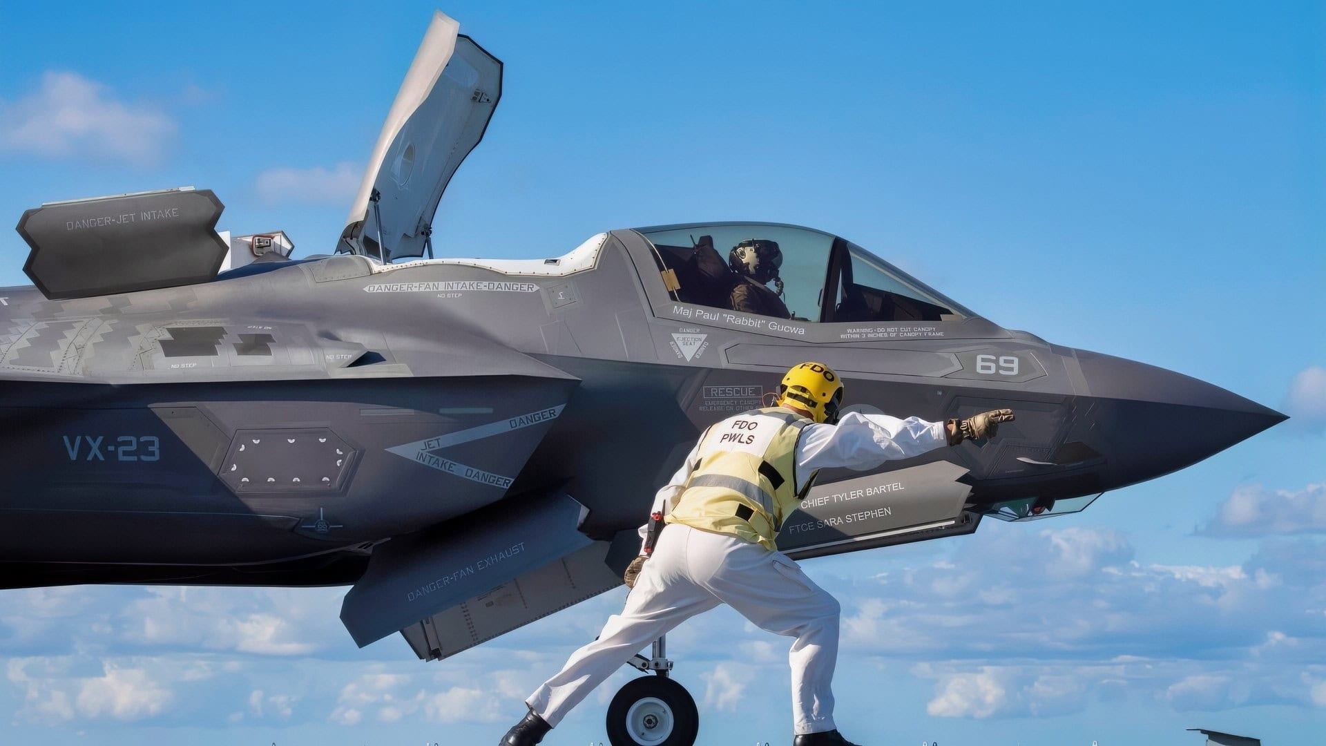 The HMS Prince of Wales (R09) aircraft carrier flight deck officer “shoots” an F-35B Lightning II short takeoff vertical landing (STOVL) variant fighter jet for a STO launch from a ski jump aboard the U.K.’s newest carrier Oct. 24, 2023. The 5th generation strike aircraft for Navy, Air Force, Marines, and allies is aboard to conduct developmental test phase 3 (DT-3) flight trials, which continue today. During the ship's deployment to the U.S. Eastern Seaboard for WESTLANT 2023, a Pax River F-35 Integrated Test Force (Pax ITF) team is working closely with the ship's company to conduct the sea trials that continue pushing the boundaries of carrier aviation. (Photo by Michael D. Jackson)