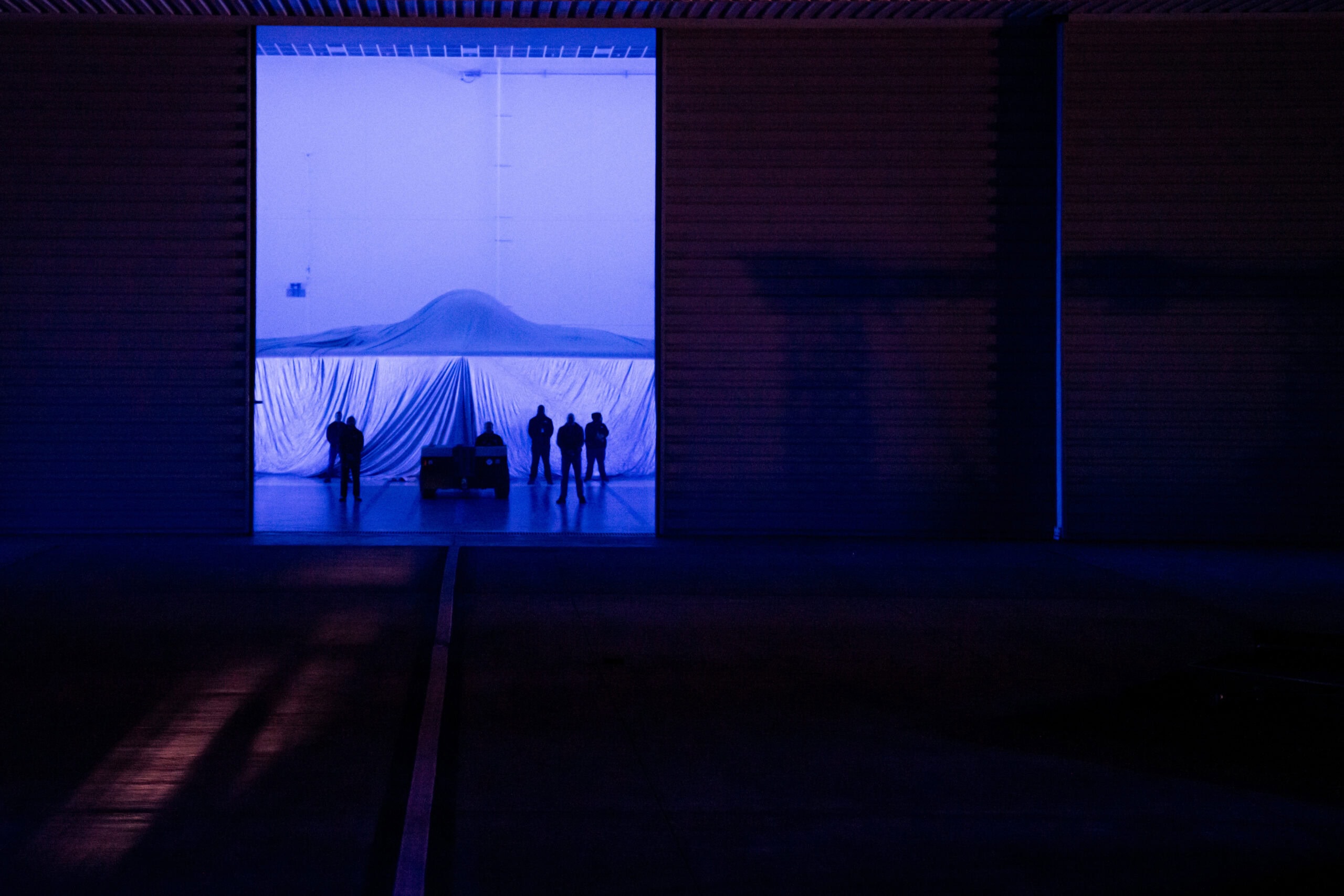 A covered Northrop Grumman B-21 Raider is displayed during a practice unveiling ceremony at Northrop Grumman’s manufacturing facility on Air Force Plant 42 in Palmdale, California, Dec. 1, 2022. The B-21 will be a long-range, highly survivable, penetrating strike stealth bomber capable of delivering both conventional and nuclear munitions. (U.S. Air Force photo by Airman 1st Class Joshua M. Carroll)