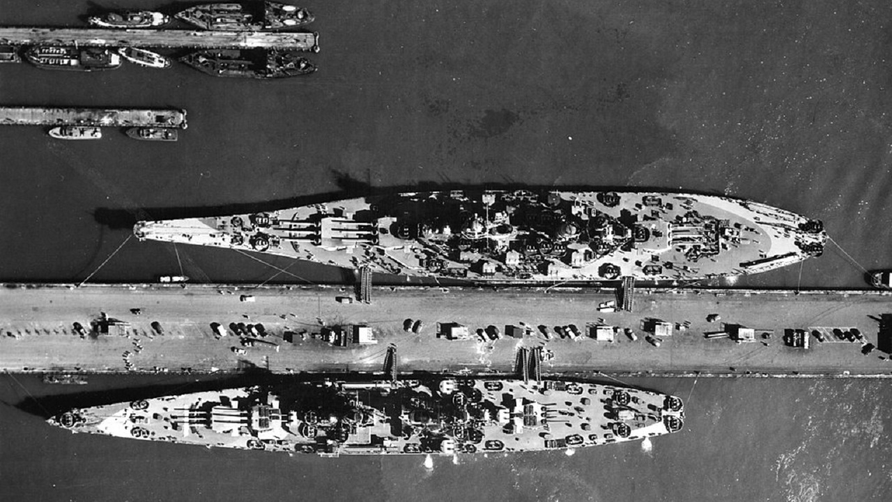1944年8月，诺福克海军基地（美国）码头上的军舰空中视图。舰艇包括：战列舰密苏里号（BB-63），最大的舰艇；战斗巡洋舰阿拉斯加号（CB-1），在码头的另一侧；护航航母克罗阿坦号（CVE-25），以及两艘驱逐舰，一艘弗莱彻级驱逐舰在码头，另一艘克莱姆森/威尔克斯级驱逐舰停泊在外侧。图像来源：创意共享。